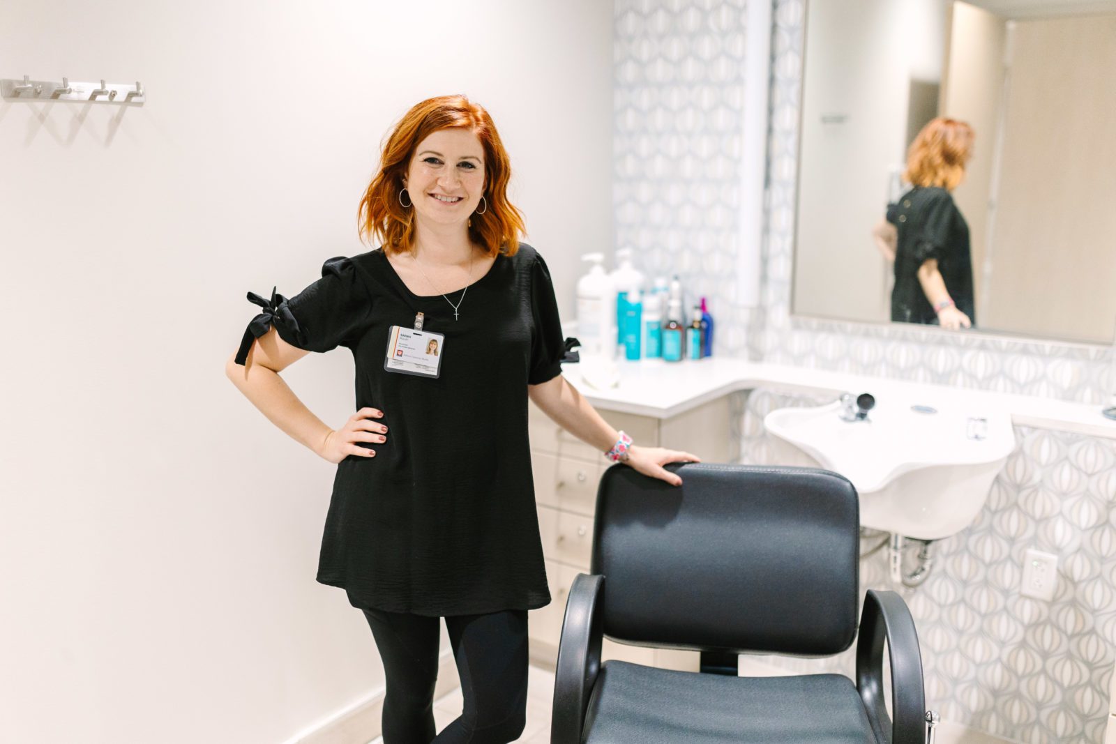 Sarah Pulley smiles by her salon chair in the Ronald McDonald Family Room